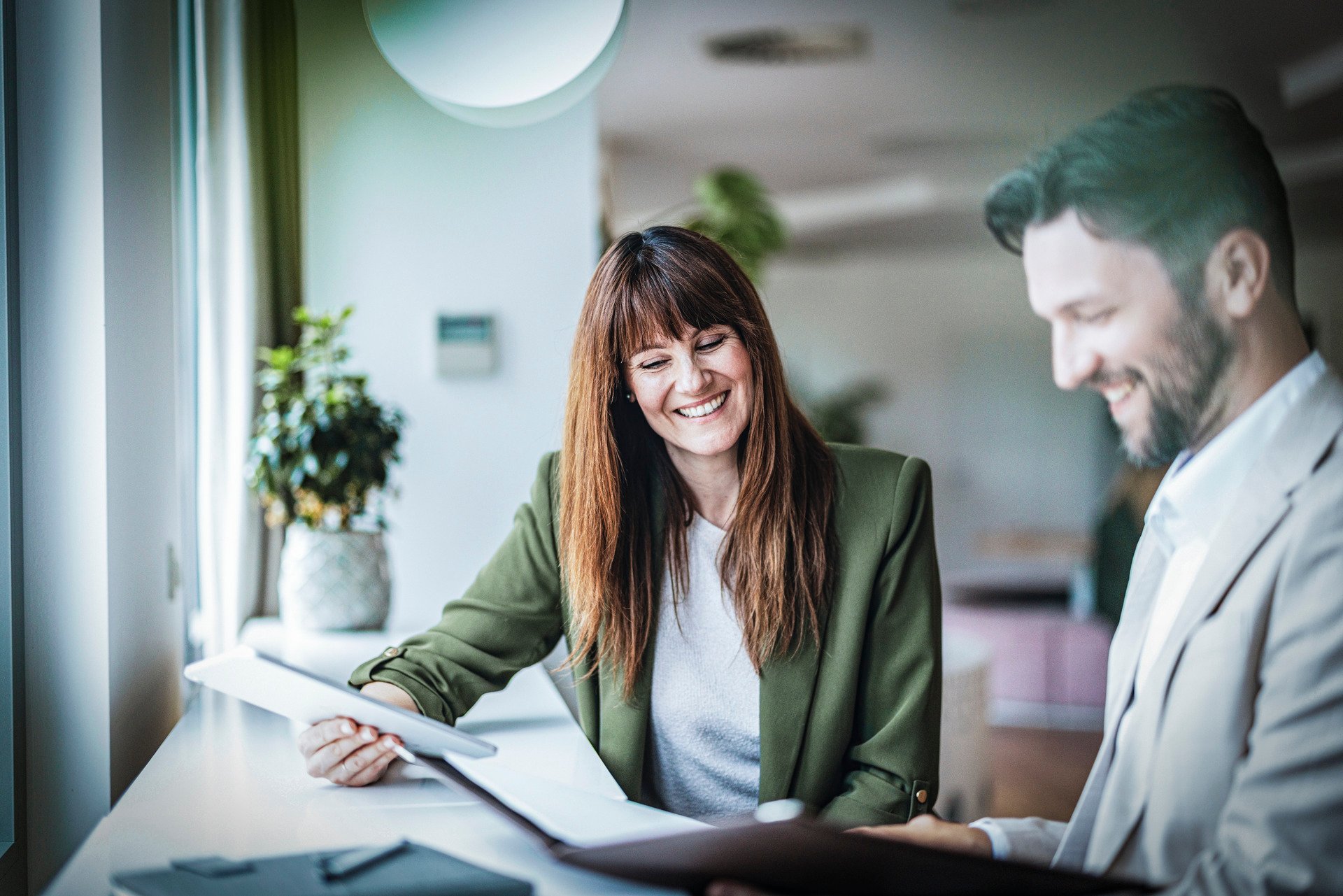 Two smiling people, a woman and a man sitting at a table.
