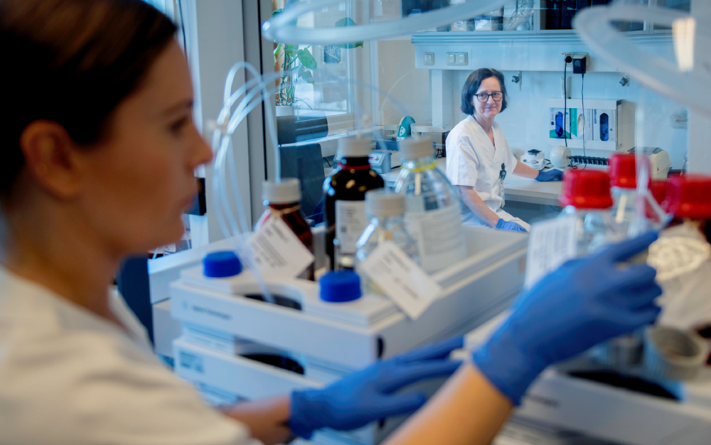 To personer i laboratorieutstyr arbeider i et moderne laboratorium.