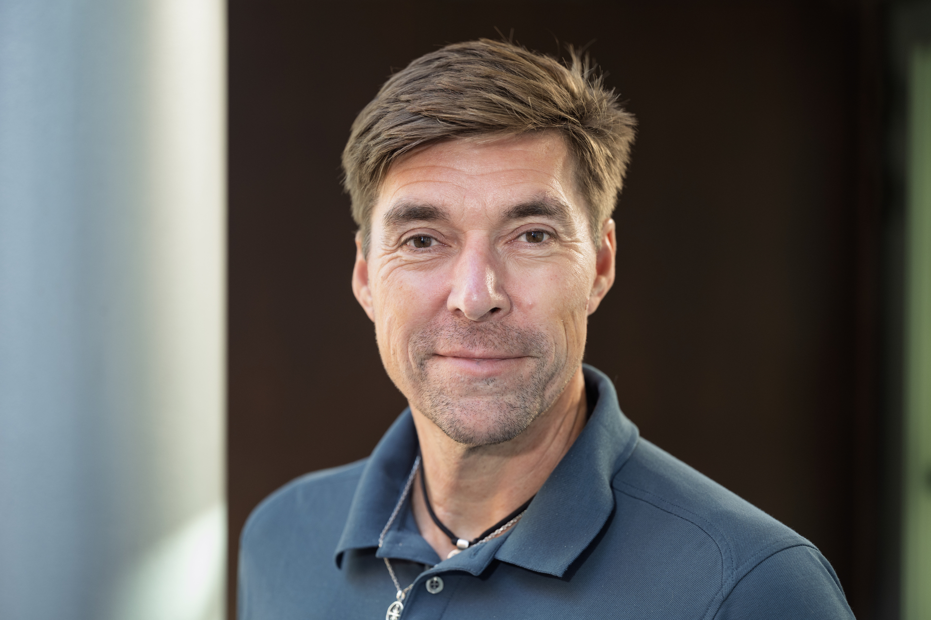 Mann med brunt hår og pique-skjorte. Nærbilde fra skuldrene opp