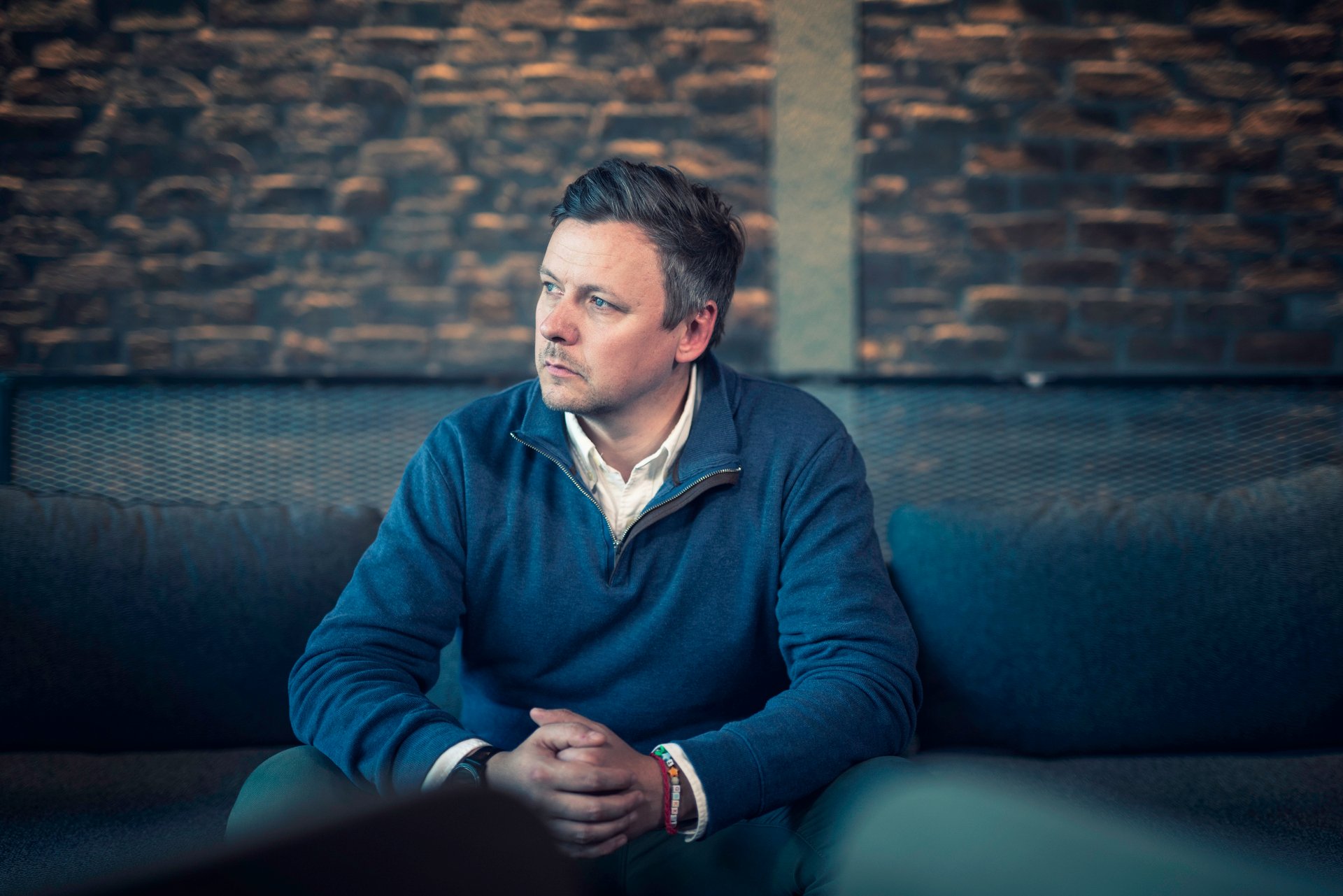 En mann sitter og reflekterer, symboliserer usikkerhet og tanker rundt nedbemanning og jobbfremtid.