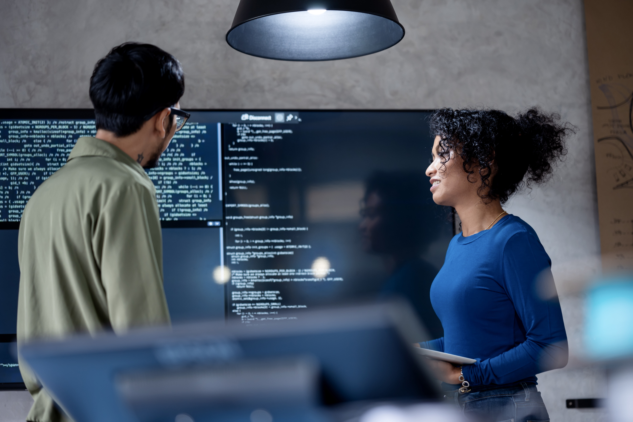 Kolleger diskuterer Python koding på en dataskjerm