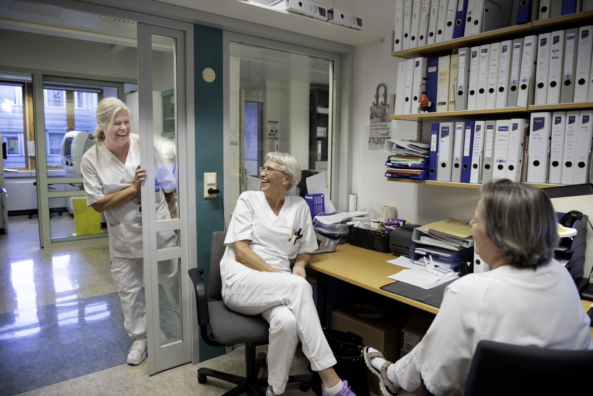 Smilende helsepersonell i et kontormiljø. Illustrerer et godt arbeidsmiljø og viktigheten av tariffavtaler for ansattes trivsel og rettigheter i helsesektoren.