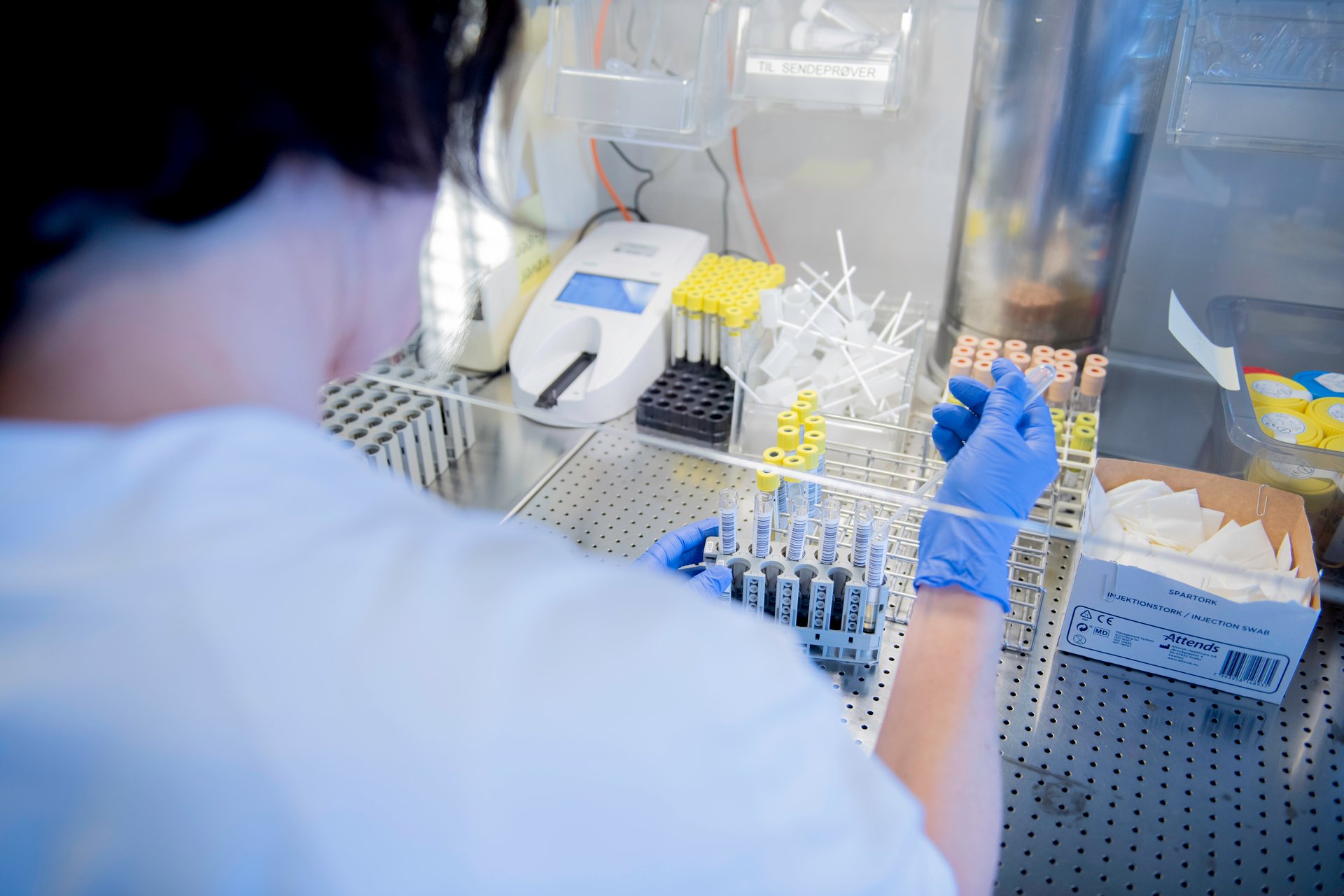 Biomedical laboratory technicians work in a laboratory, surrounded by test tubes and other laboratory equipment.