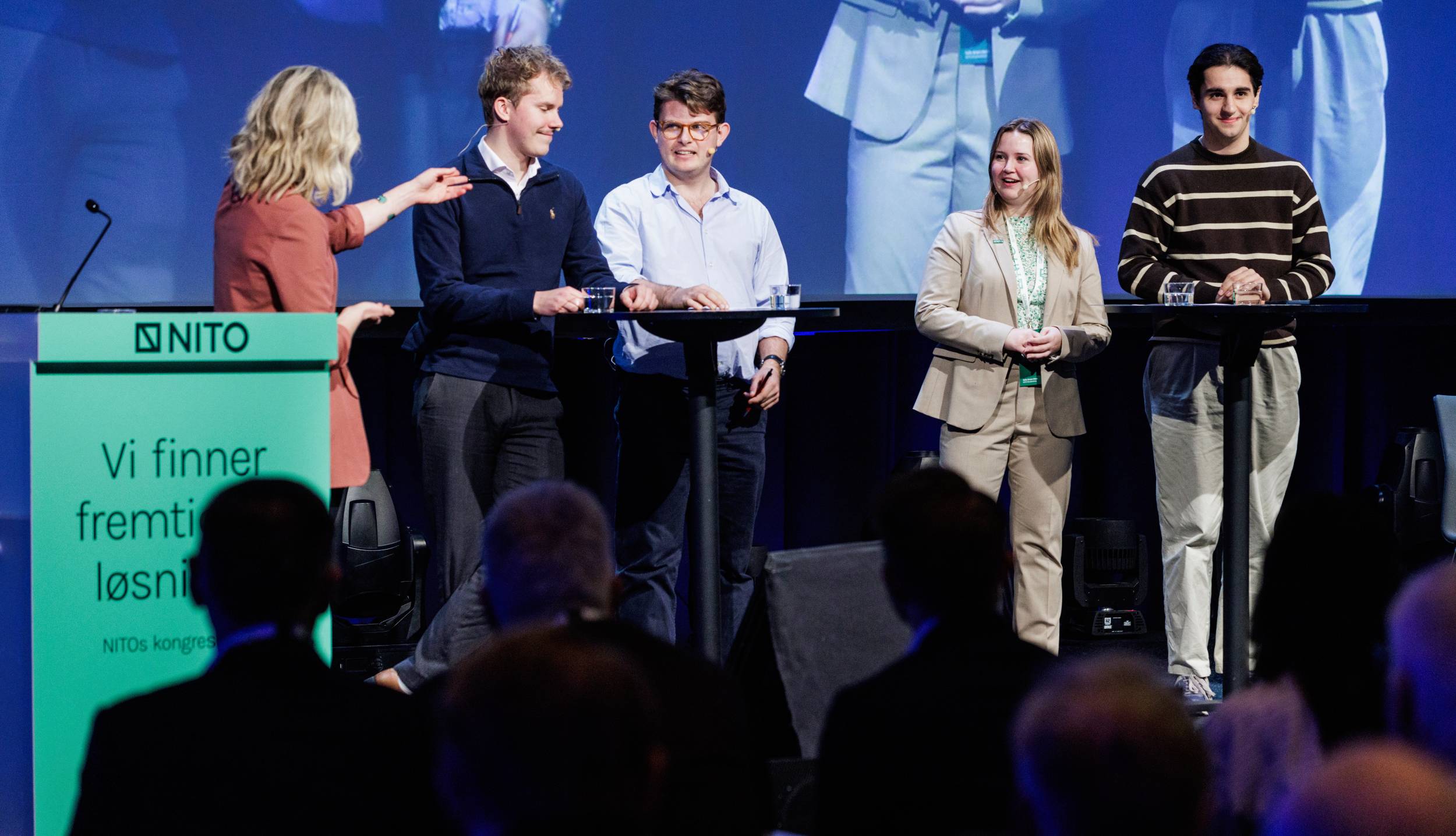 Paneldebatt på scene med fire unge og én voksen kvinne foran et publikum.