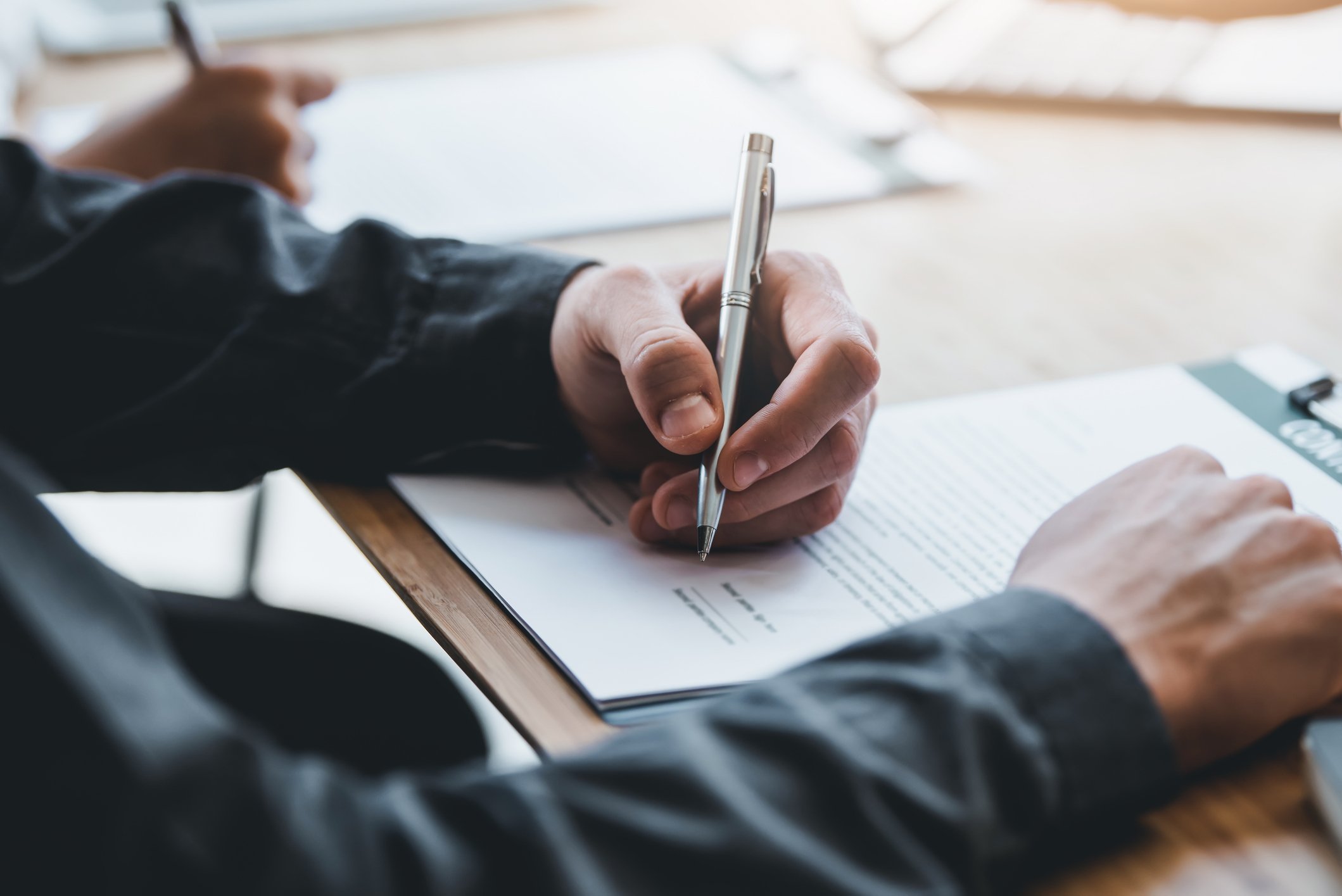 Illustration image: Sees hands holding pens and signing papers