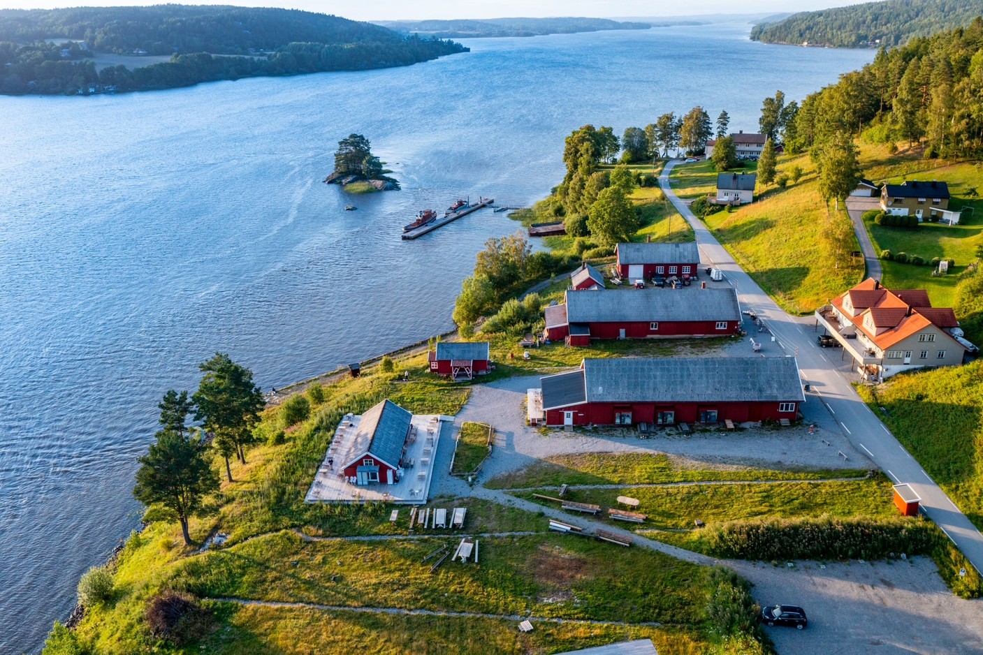 Bilde av røde låver på Furuholmen. Sjøen i bakgrunn.