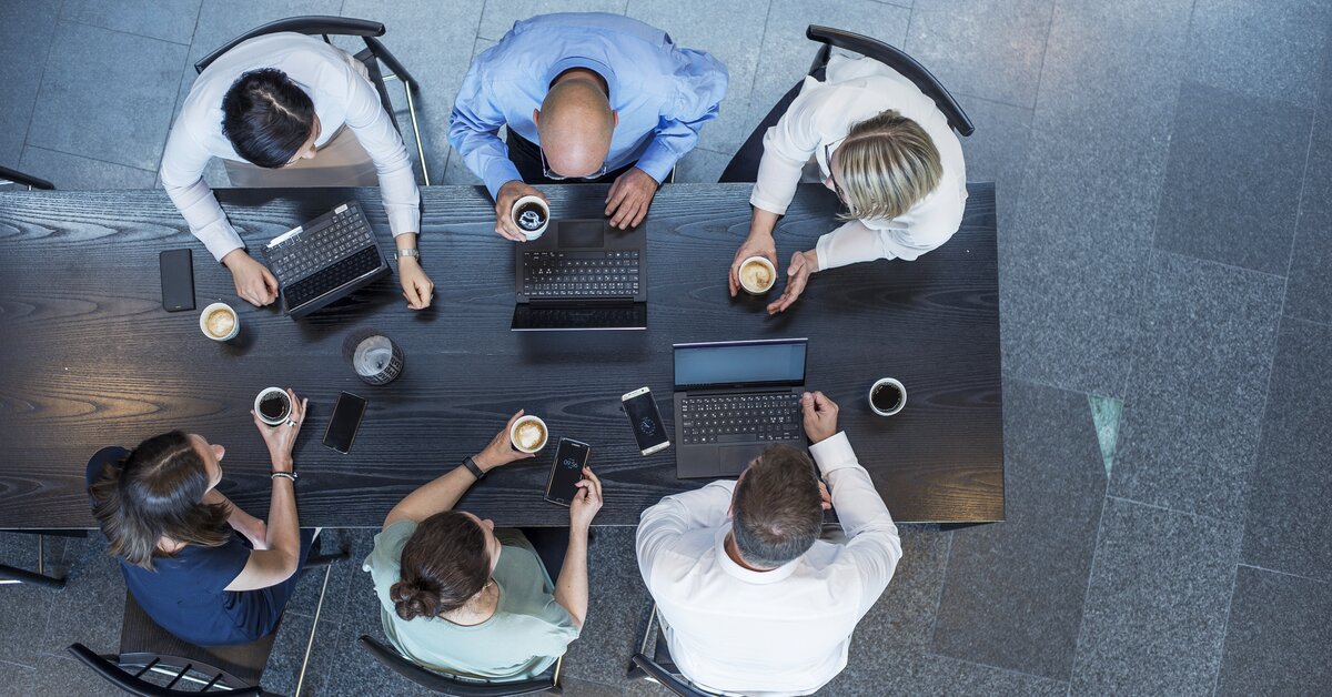 6 people sitting around a table with their own computer