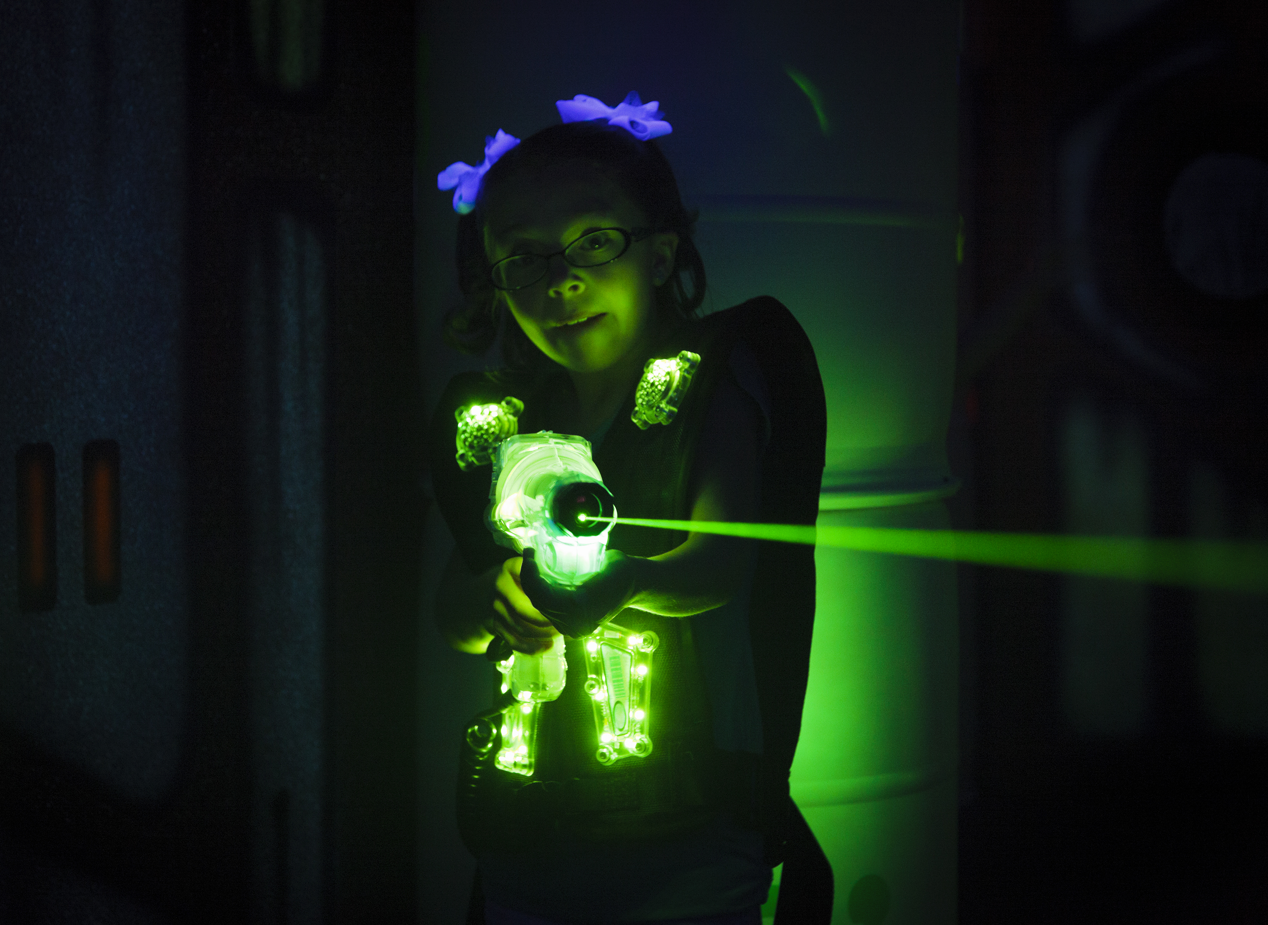Jente med lasertagvåpen som lyser ut en grønn laserstråle