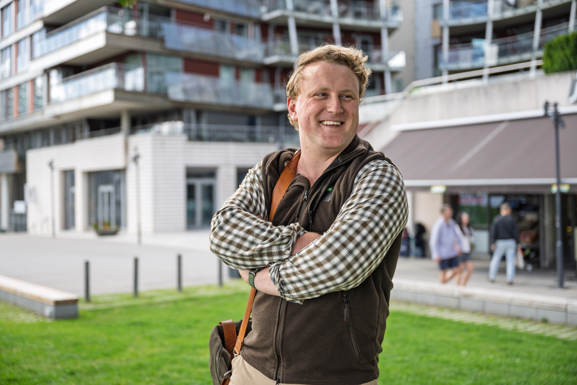 Mann står med armene i kors foran bygg. 