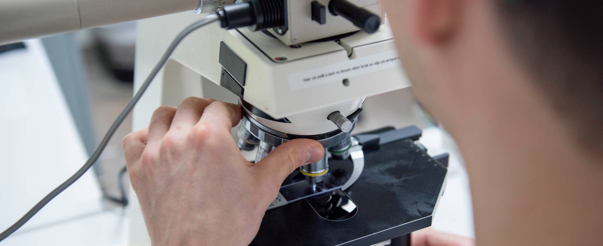 A biomedical laboratory technician who is in the process of performing a microscopy examination.