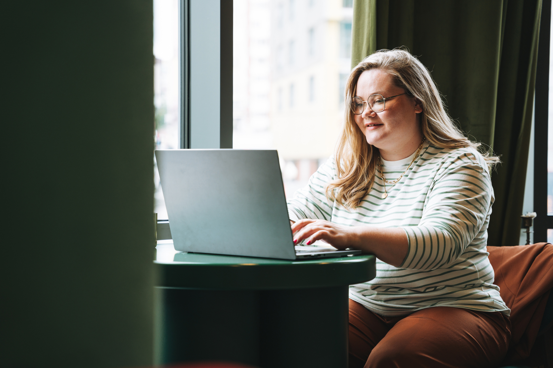 Informally dressed, female office worker uses a computer to research salary statistics to prepare for a salary interview.