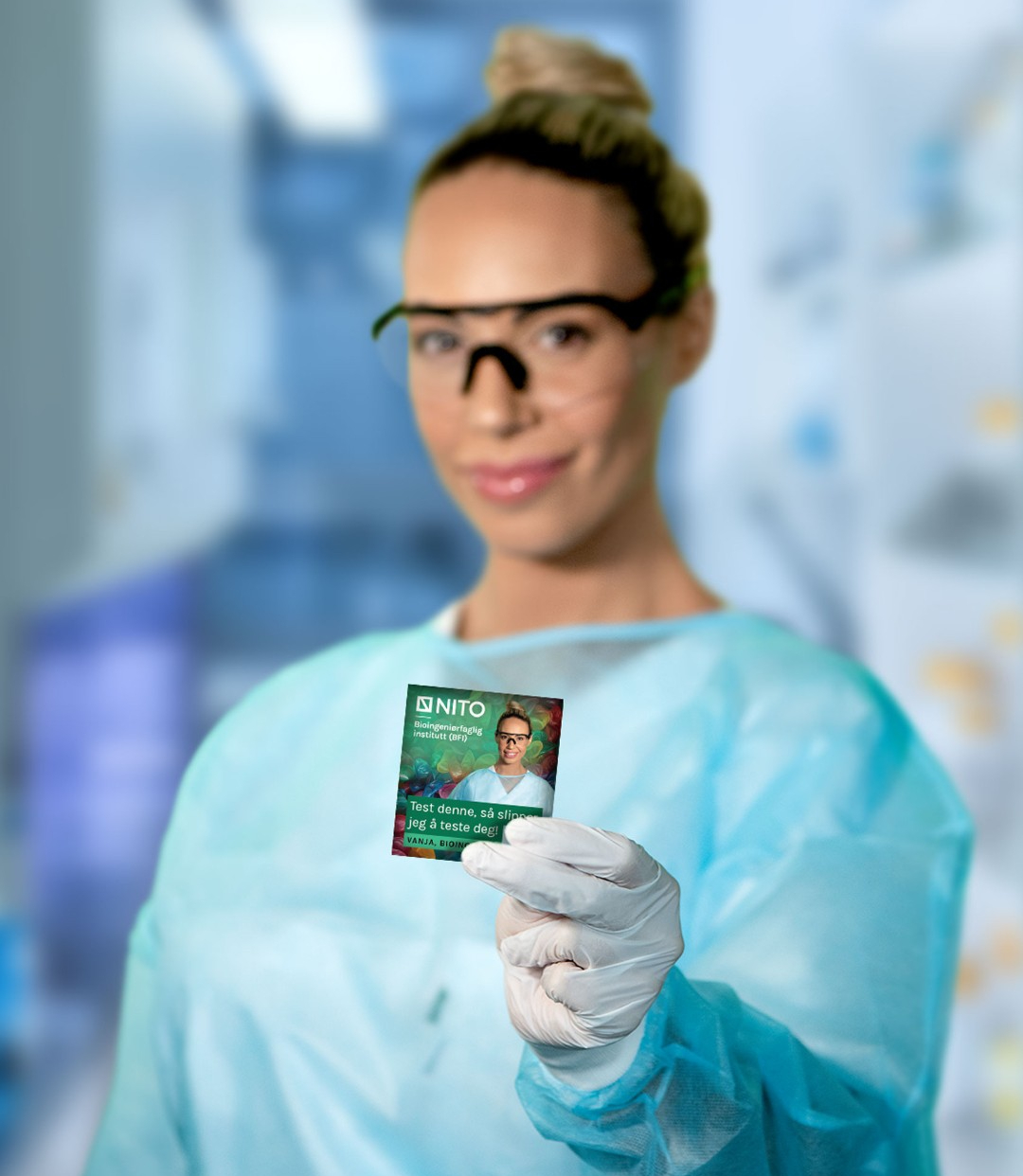 Kvinnelig bioingeniør iført verneutstyr som holder opp en kondompakke