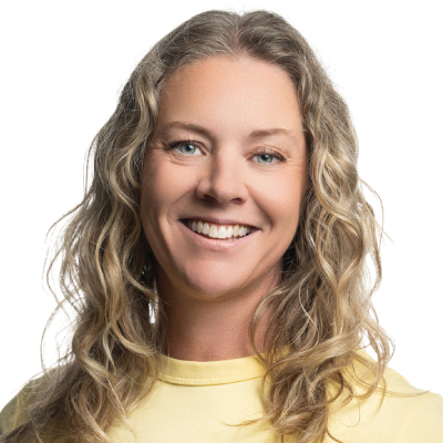 Smilende kvinne med langt blondt hår og en gul trøye.