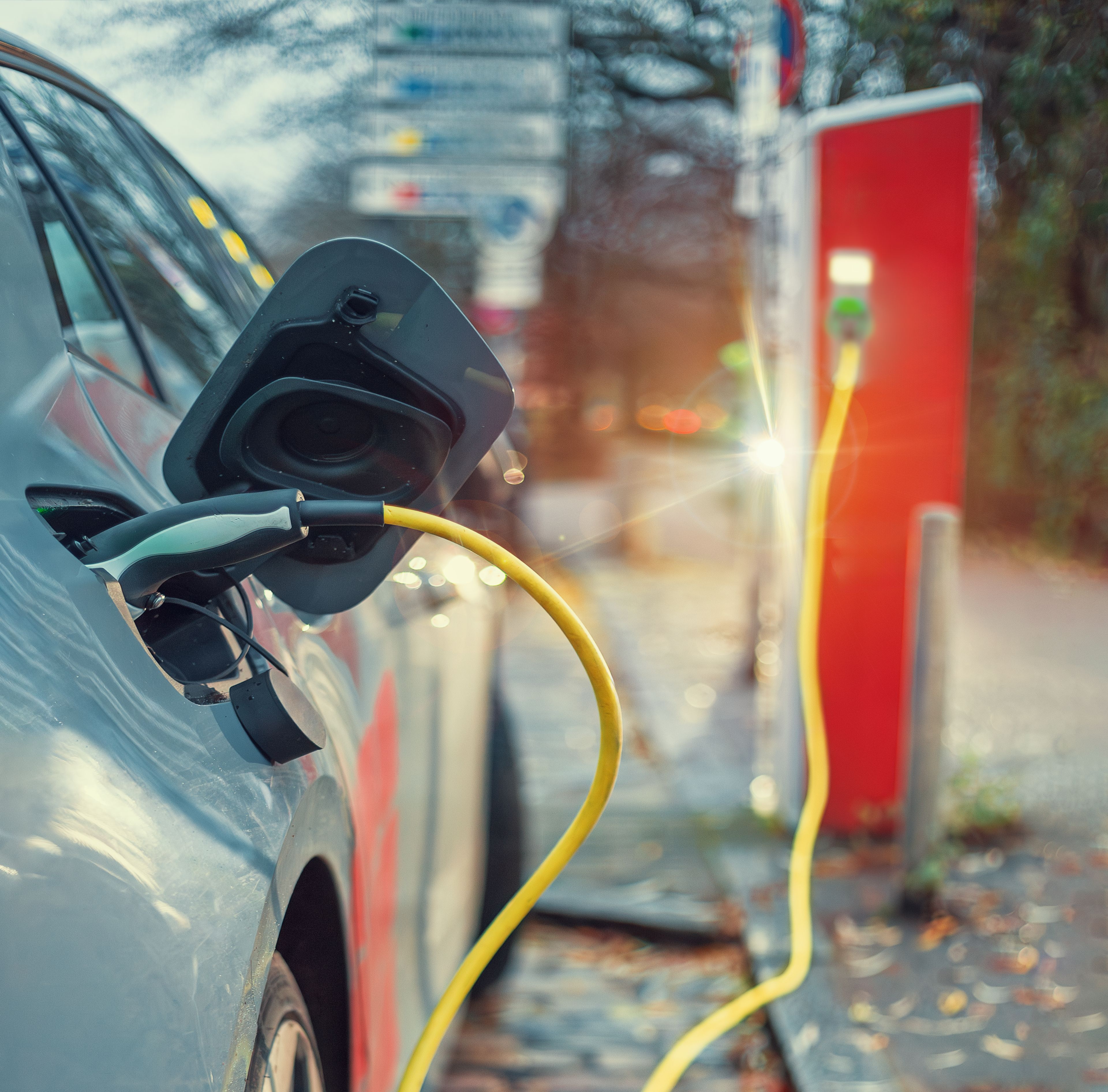 elbil som er plugget til ladekabel, med ladetårnet bak bilen