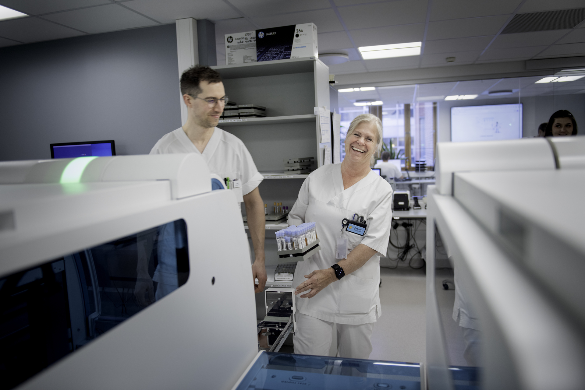 Two biomedical laboratory technicians in pleasant conversation at a hospital. Illustrates the importance of dialogue about pay and working conditions in the Spekter sector.