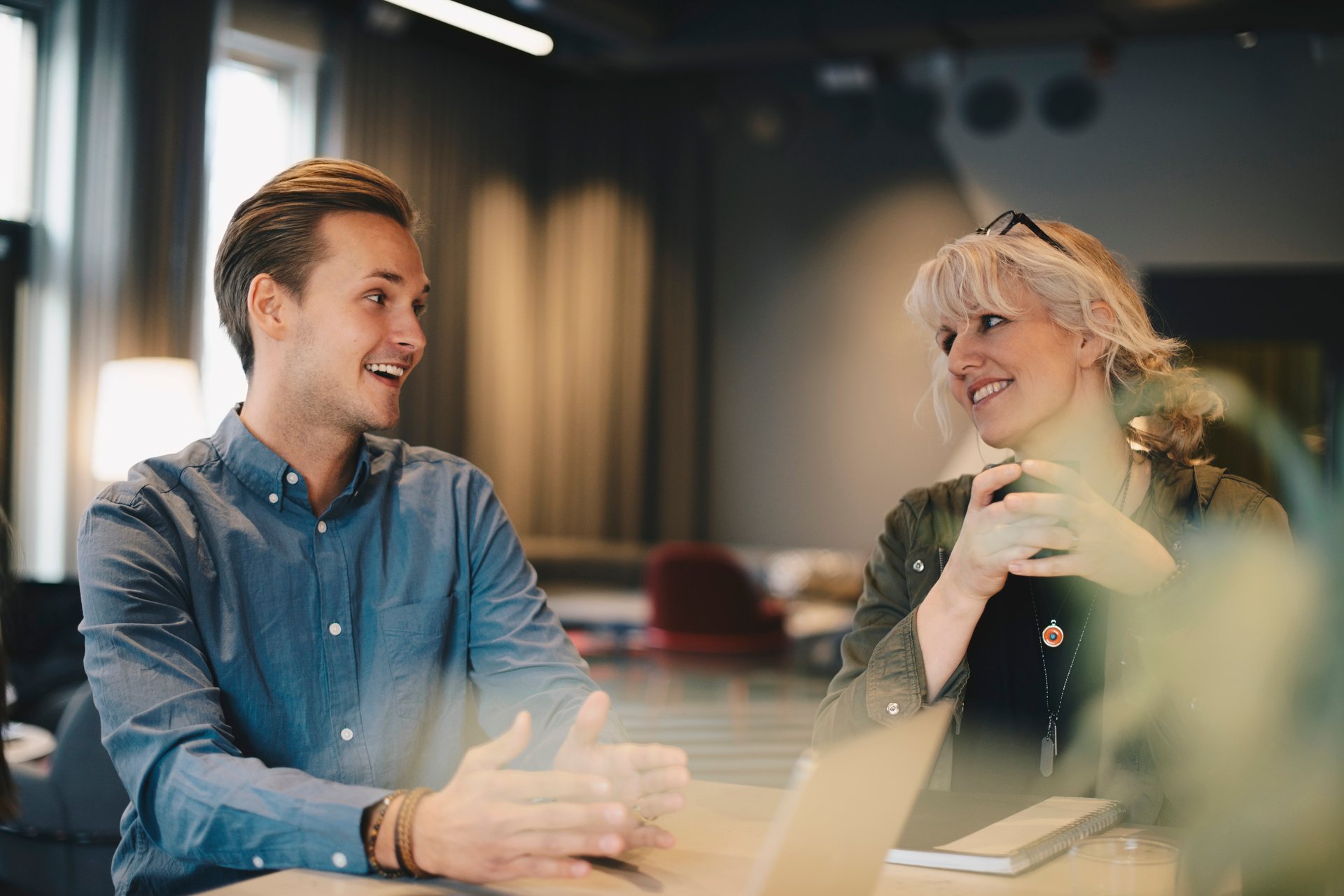 Mannlig og kvinnelig kollega har en samtale i moderne kontormiljø, illustrerer hvordan en god lønnssamtale kan se ut.