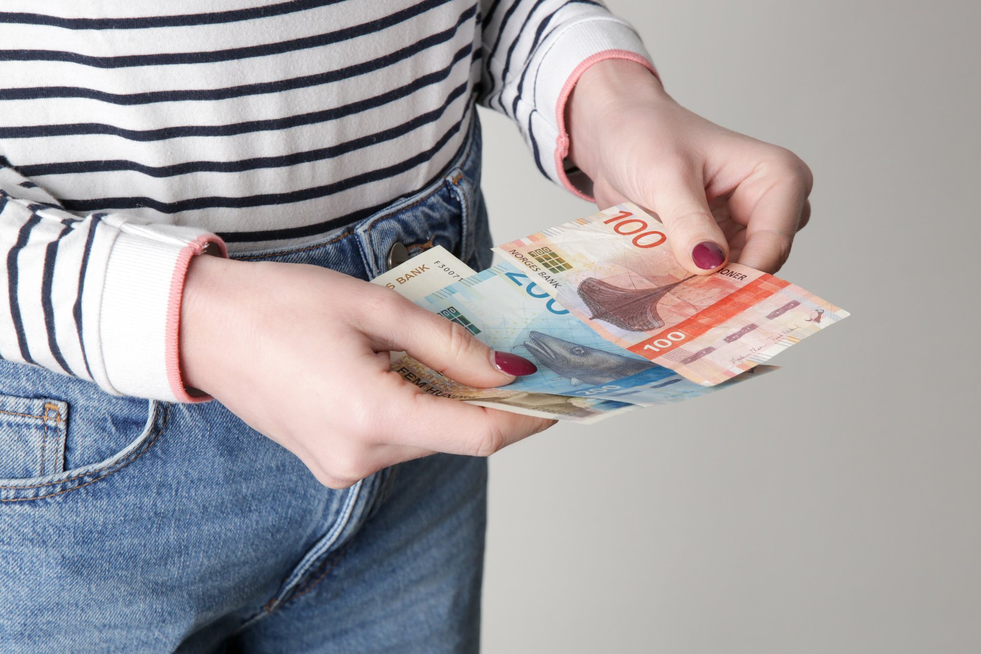 En person teller norske pengesedler, illustrerer lønn og resultatet av lønnsoppgjøret.