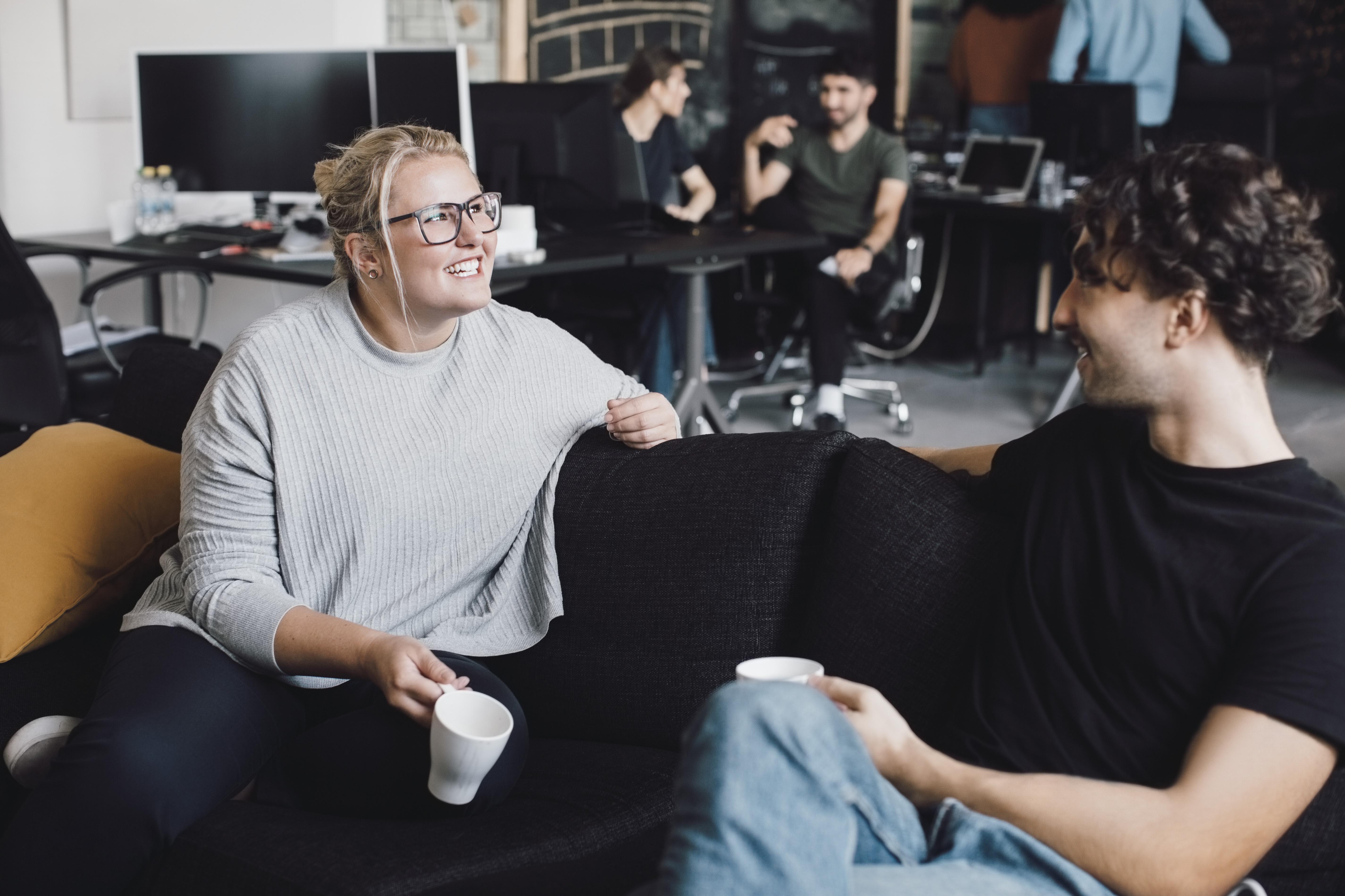 Smilende tillitsvalgt i samtale med medlem over en kaffekopp– engasjert fagforeningsrepresentant i arbeidshverdagen.