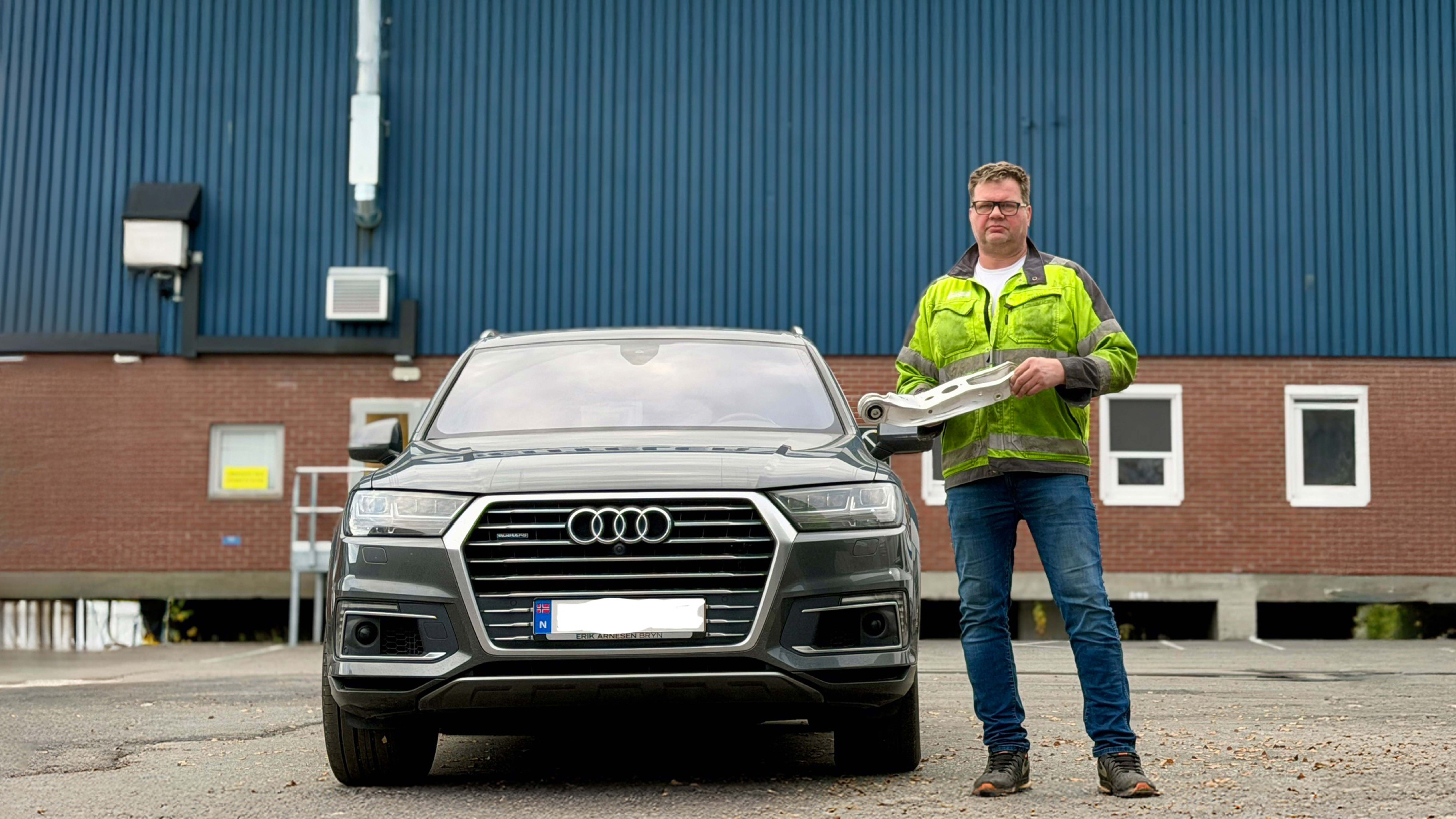 Man in signal yellow work jacket standing next to a car