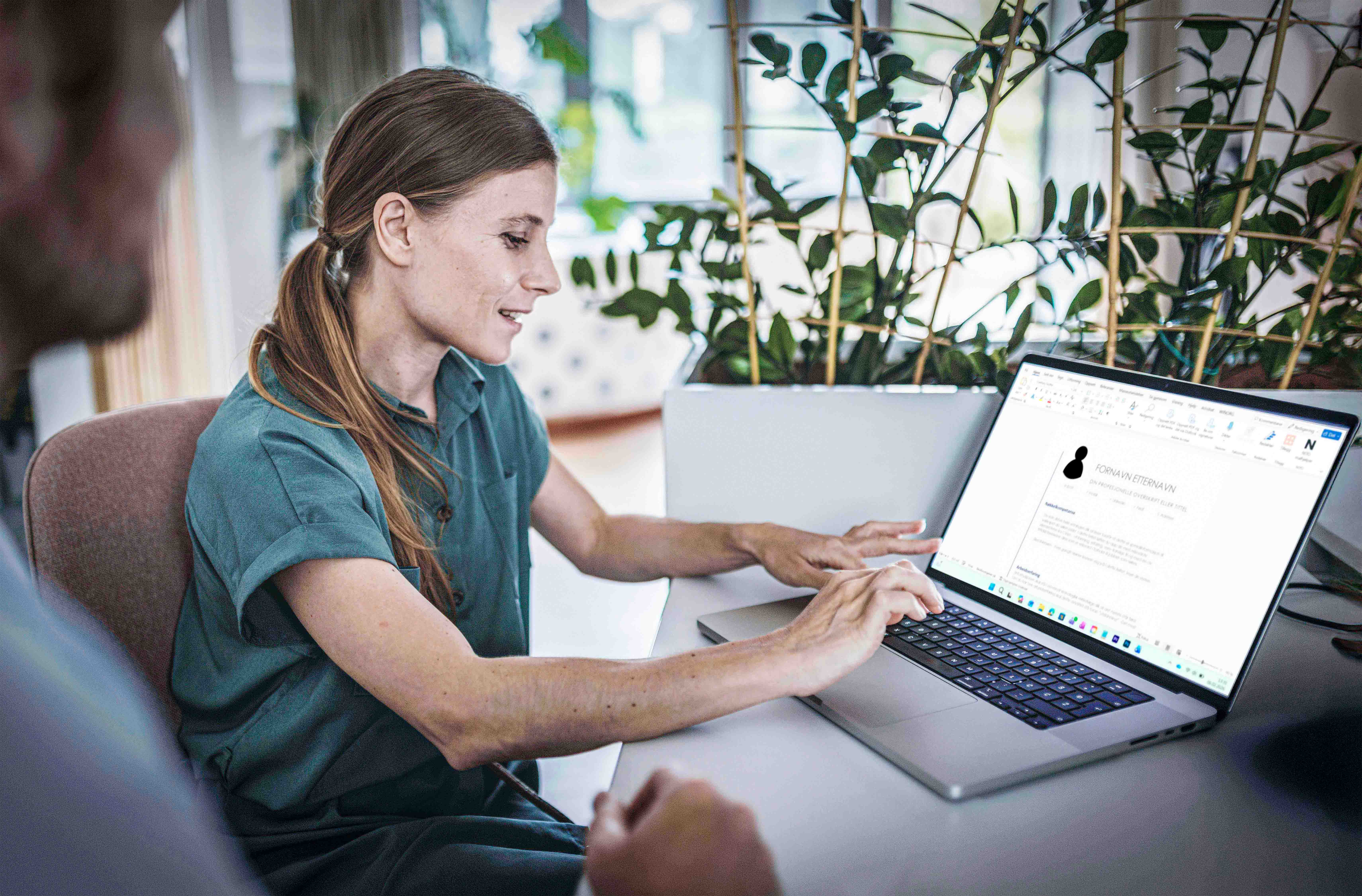 Woman in green top sitting and working on a computer