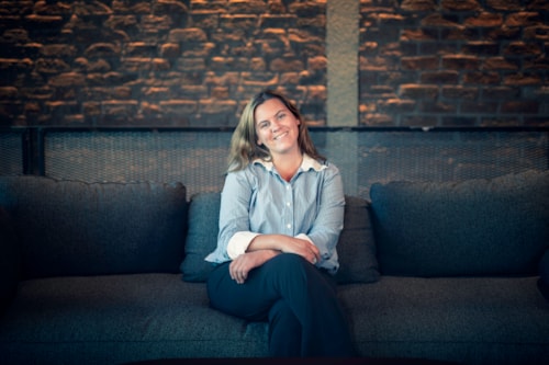 Ung smilende dame som sitter på en sofa