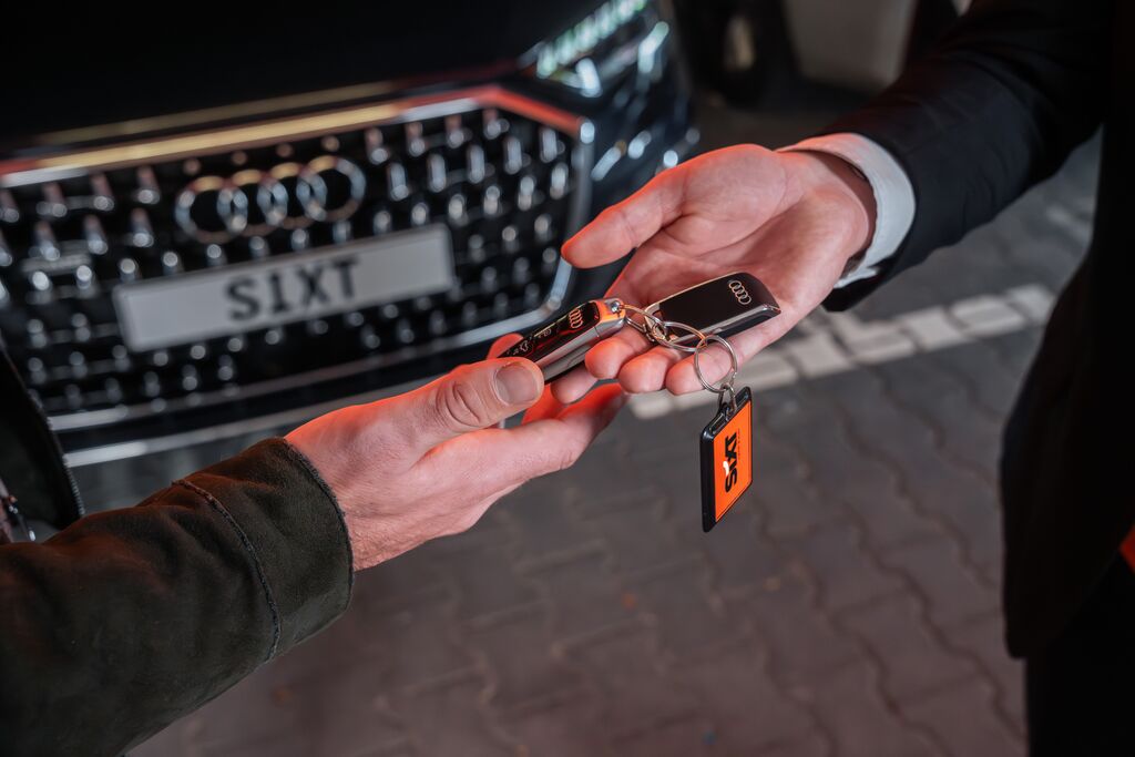 Mann i bil, som ser ut av vinduet og inn i kameraet